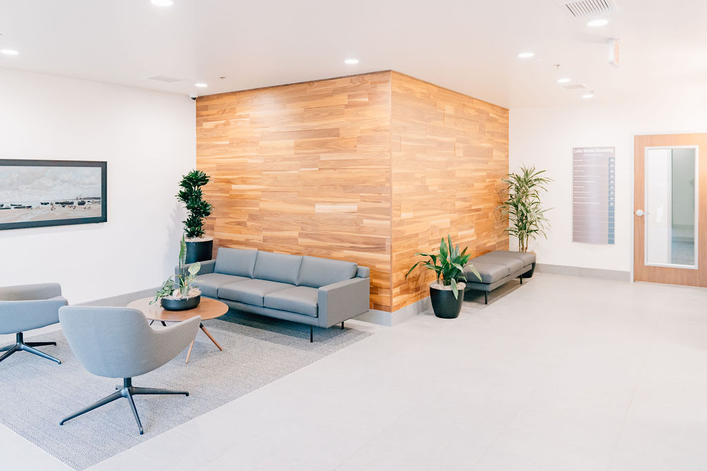 Greeting area with couch, bench, chairs, and plants for private executive suites